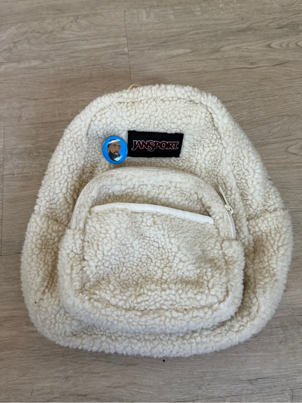 JanSport Half Pint FX Mini Backpack in a cream-colored sherpa or boucle fabric.